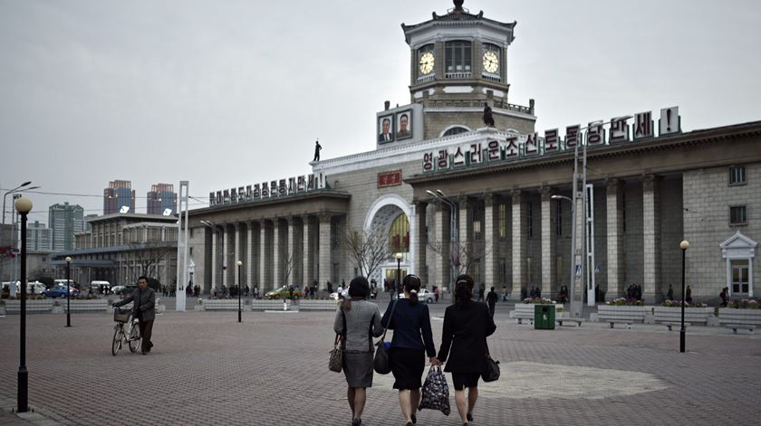 Norte-coreanas caminham em direcção à estação de Pyongyang, dominada pelas imagens dos dois ex-líderes