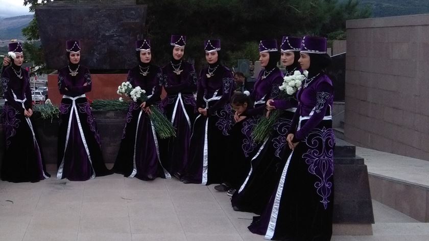Mulheres de Nagorno Karabakh, com traje típico, prestam homenagem a mortos na guerra. Foto: Filipe Avillez/RR