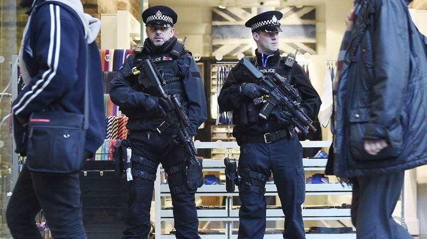Dois polícias britânicos armados "até aos dentes" vigiam os transeuntes na estação de comboios St. Pancras International, de onde partem os comboios da rede Eurostar para Bruxelas. Foto: Andy Rain/EPA